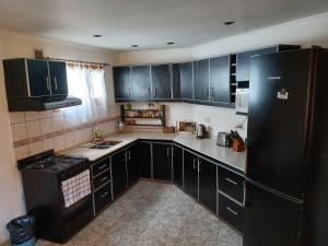 a kitchen with black cabinets and a black refrigerator at Depto Castillo in El Bolsón