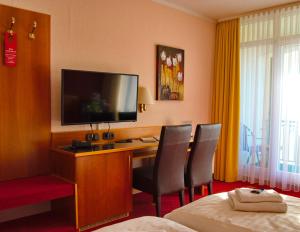 a hotel room with a desk with a flat screen tv at Hotel Goldener Fasan in Oranienbaum-Wörlitz +38 photos