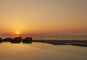 a pool with a sunset in the background at Hotiday Santorini Oia in Oia