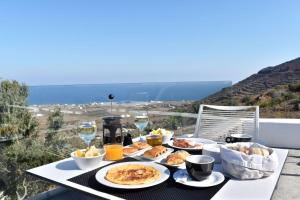 a table with plates of food and glasses of wine at Hotiday Santorini Oia in Oia