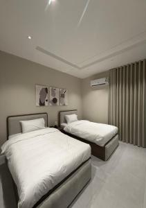 two beds in a hotel room with white sheets at Riwaq suite in Jeddah