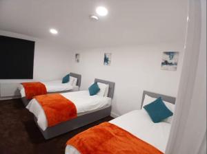 a bedroom with two beds with orange and white sheets at Lincoln Manor 5BR in Peterborough +7 photos