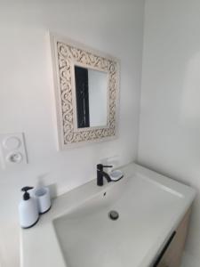 a white bathroom with a sink and a mirror at Le nid de Marceline in Lannion