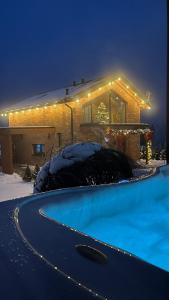a house with a swimming pool in the snow at night at Czaple Resort in Stare Czaple