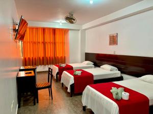 a hotel room with three beds and a table and chairs at Hotel Luxor Pucallpa in Pucallpa