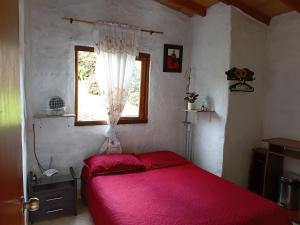 a bedroom with a red bed and a window at Cabaña campestre in Medellín