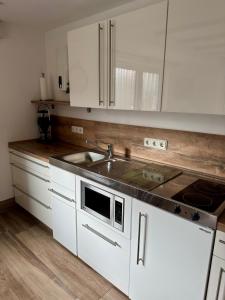 a kitchen with white cabinets and a sink at Haus Edeltrud - Ferienwohnung Moselufer in Bernkastel-Kues +4 photos