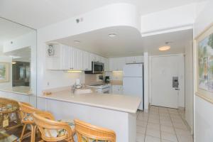 a kitchen with white cabinets and a counter and chairs at Ilikai Tower 633 in Honolulu