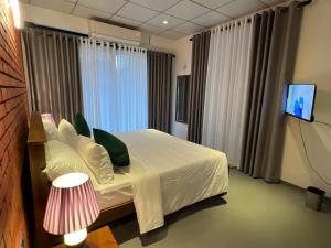 a bedroom with a bed with white sheets and a television at Sol & Luna in Katunayaka