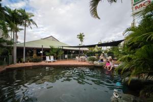 
people are swimming in a pool near a beach at Glenmore Palms Motel in Rockhampton
