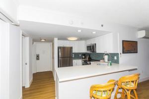 a kitchen with white walls and a counter with chairs at Ilikai Tower 943 in Honolulu +15 photos
