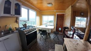 a kitchen with a stove and a sink and a table at Cabañas Victoria Aucaco in Ancud