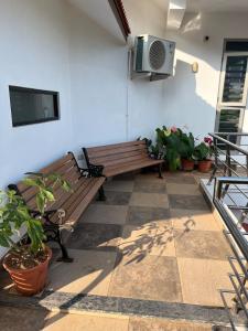 a patio with two benches and a tv on a wall at Nethra Darshan in Mangalore