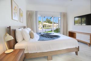 a bedroom with a bed with a desk and a television at Destination Jelly Playa Coral Condo in Punta Cana +59 photos