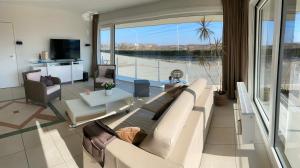 a living room with a couch and a large window at SunnySide-of-TheSea - stunning view on nature, big terraces all around - 150 m from sea, beach, stores, restaurants & beach bars - with parking in Nieuwpoort