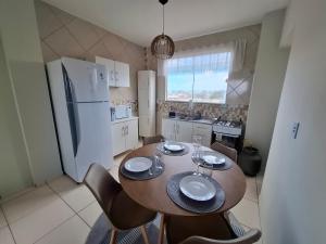 a kitchen with a wooden table with chairs and a refrigerator at Calma e tranquilidade em Barra Velha in Barra Velha