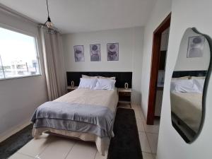 a bedroom with a bed and a mirror at Calma e tranquilidade em Barra Velha in Barra Velha