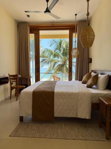 a bedroom with a large bed and a large window at Piña Boutique Hotel - Beachfront in Habaraduwa Central