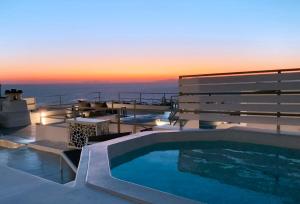 a swimming pool on top of a house with the sunset at OUTOPOIA CAVE STUDIOS in Oia