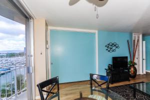 a dining room with blue walls and a glass table and chairs at Ilikai Marina 984 in Honolulu