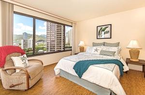 a bedroom with a bed and a chair and a large window at Discovery Bay 1419 in Honolulu