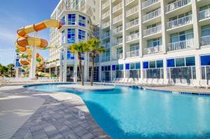 a resort swimming pool with a slide in front of a building at Crown Reef Beach Resort and Waterpark in Myrtle Beach