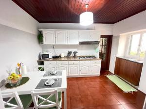 a kitchen with white cabinets and a white table at Casa Gouveia in Ribeira Brava