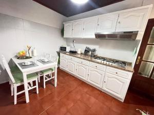 a kitchen with white cabinets and a table with chairs at Casa Gouveia in Ribeira Brava +12 photos