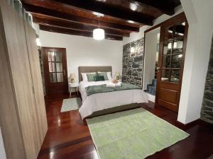 a bedroom with two beds and a stone wall at Casa Gouveia in Ribeira Brava