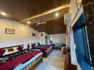 a hotel room with two beds and a couch at Amor Villa Abu in Mount Ābu