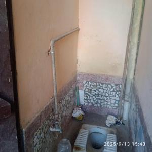 a small bathroom with a toilet and pipes on the wall at Balaji Shridham in Jāmb
