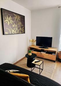 a living room with a couch and a flat screen tv at L'Oasis de Fougères in Fougères
