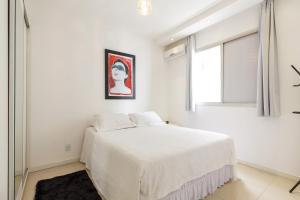 a white bedroom with a bed and a window at Apartamento Floripa in Florianópolis