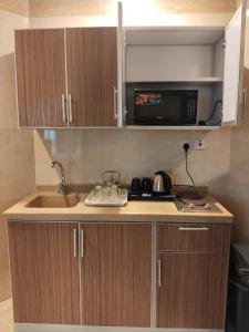 a small kitchen with a sink and a microwave at همم للشقق المخدومة أملج-HMM Appartment Service in Umm Lajj
