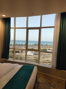 a bedroom with a large window with a view of the beach at همم للشقق المخدومة أملج-HMM Appartment Service in Umm Lajj