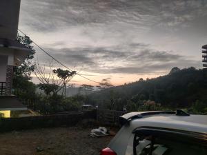 a car parked in front of a house with a sunset at Misty Vibes Homestay Vagamon in Vagamon