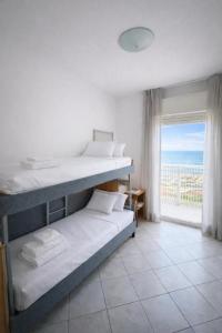 a bedroom with two bunk beds and a large window at Hotel ABA FRONTE MARE in Milano Marittima
