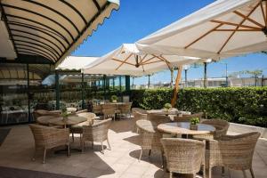 a patio with tables and chairs and white umbrellas at Hotel ABA FRONTE MARE in Milano Marittima