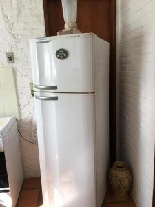 a white refrigerator sitting in a kitchen next to a wall at Passarim Chalé in Monte Verde