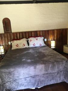 a bedroom with a large bed with two pillows at Passarim Chalé in Monte Verde
