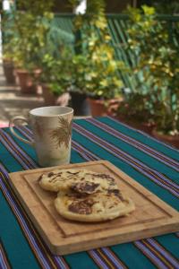a wooden cutting board with two pieces of bread on a table with a cup at Lombardia Planes de Renderos in San Marcos