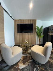 two chairs and a table in a living room with a tv at L'instant étoilé in Châteauneuf-lès-Martigues