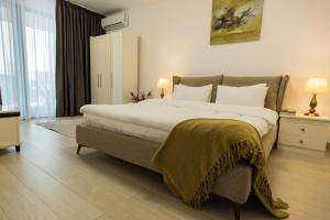 a bedroom with a large bed with a blanket on it at Le Blanc ApartHotel in Bucharest
