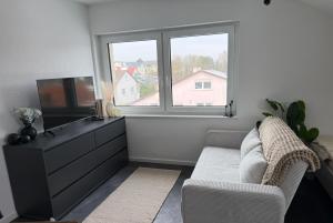 a living room with a couch and a tv and a window at Ferienwohnung Verissimo in Ittlingen