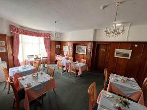 a dining room with tables and chairs and a chandelier at The Ormerod in Burnley