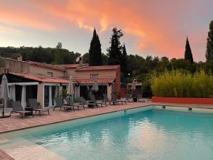 a pool with chairs and a house with a sunset at Les Mazets de la Cascade in Salernes