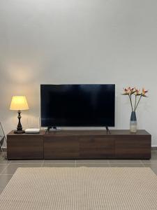 a flat screen tv sitting on top of a wooden entertainment center at Deyrina Home in Arau