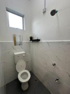 a white bathroom with a toilet and a window at Deyrina Home in Arau +13 photos