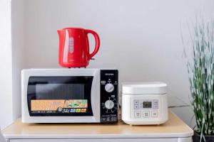 a red cup on top of a microwave next to a toaster oven at Yoshidoku Inn Domemae 1 - Close to USJ World Airport 吉徳家庭旅館1 京セラドーム前 -近USJ -空庭温泉-難波-心斎橋-関西空港大阪駅梅田駅乗り換えなし-荷物の預かり無料-近く駐車場多い in Osaka