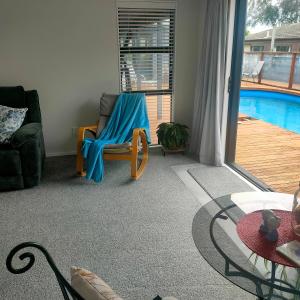 a living room with a chair and a pool at One8Endeavour in Tauranga +5 photos